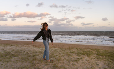 happy young woman with flying hair enjoying her free time at sunset on lonely beach.