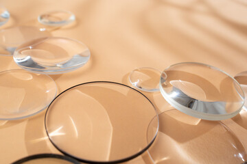 Clear magnifying lenses on bright cream background, with palm leaves shadows, quiet abstract...