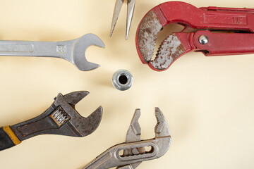 Many wrenches around a screw on beige background, teamwork concept