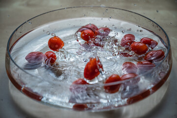 Closeup of Fresh red organic baby cherry plum tomatos (baby tomato,cherry tomato) group dropping on the water bowl