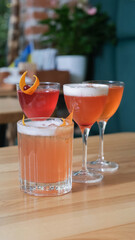 Four alcoholic cocktails in glasses on a wooden cafeteria table
