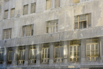 Fototapeta premium Gray safety net around a large abandoned townhouse in poor condition, grey protective coating