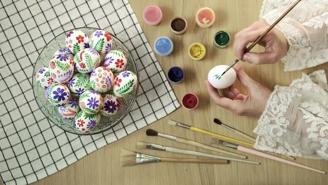 Process of making handmade painted Easter eggs. Close-up of hands painting Easter egg with paint and brush. Preparing for Easter, Christian tradition 