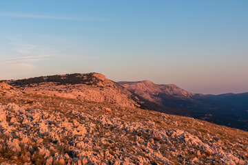 Panoramic view rocky hillside during sunrise in the mountains near coastal town Baska, Krk Otok, Primorje-Gorski Kotar, Croatia, Europe. Deserted barren landscape. Vibrant coloured sky. Tranquil scene