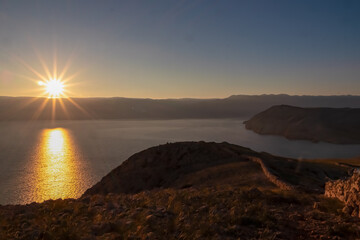 Fototapeta premium Panoramic view of sunrise over karst mountains along idyllic hiking trail near coastal town Baska, Krk Otok, Primorje-Gorski Kotar, Croatia, Europe. Majestic coastline Mediterranean Adriatic Sea