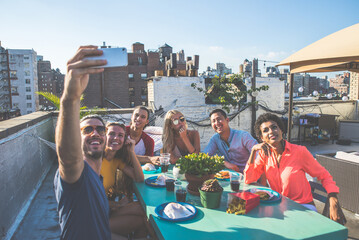 Group of friends apending time together on a rooftop in New york city, lifestyle concept with happy...