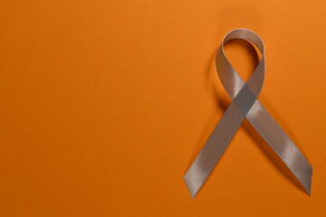 Gray ribbon on orange background. Parkinson day.