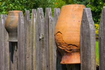 Clay brown jugs on a rural fence - 756719517
