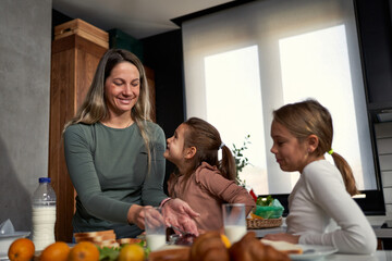  Sweet morning ritual: Mother and daughters joyfully spreading jam on bread, savoring the simple delight of a shared, sweet breakfast.