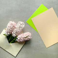 Pink spring hyacinth flowers neatly arranged in an envelope, copy-space on colored paper, square composition