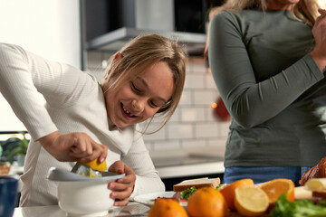  Laughter echoes in the kitchen as mother and daughters squeeze oranges, creating a refreshing touch to their delightful breakfast.