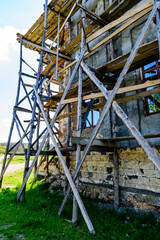 Fototapeta premium Wooden scaffolding near the old building. Ancient building restoration