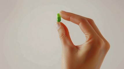 close up shot of a hand holding a bright green pill with the thumb and the index finger, white background, copy space, 16:9