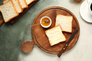 Wooden board of toasts with butter and honey on grunge background