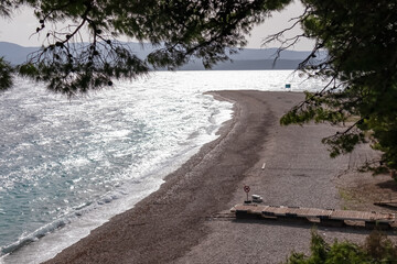 Panoramic view of idyllic beach the Golden Horn (Zlatni Rat) in tourist town Bol, island Brac, Dalmatia, Croatia. Travel destination in summer. Cloudy overcast day. No people, no dogs allowed. Serene