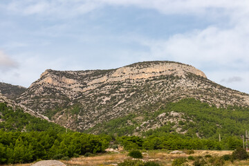 Panoramic view of majestic mountain peak Vidova Gora in Bol, island Brac, Dalmatia, Croatia. Untamed karst landscape of Dinaric Alps. Looking from beach Zlatni Rat on cloudy summer day. Wanderlust