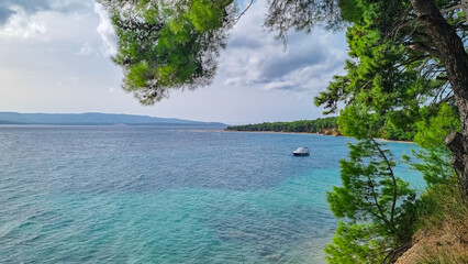 Distant view of idyllic beach the Golden Horn (Zlatni Rat) in tourist town Bol, island Brac, Dalmatia, Croatia. Travel destination in summer. Cloudy overcast day. No people, no dogs allowed. Serene