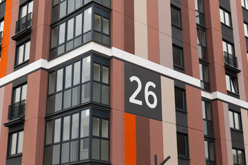 Obraz premium Modern multi-level apartment building with glass loggias. Background. Building number 26. Bright colorful residential building