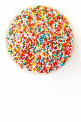 Confectionery sprinkles in bowl on white background. Decoration for cake and bakery. Top view. Space for a text