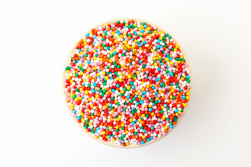 Confectionery sprinkles in bowl on white background. Decoration for cake and bakery. Top view