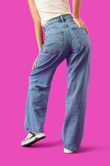 Young woman in stylish jeans on purple background, back view