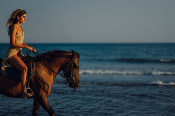 Side view of a equestrian riding a horse at summertime on a beach.