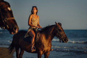 A young attractive adventurous lady is horseback riding at beach.