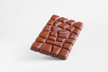 Rectangular bar of chocolate falling on white surface. Photo. Natural lighting