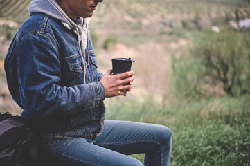 Shot of a young man stopping for a drink of water or coffee break while exploring the outdoors.