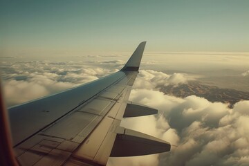 View of a commercial airplanes wing soaring high above the fluffy white clouds in the blue sky.