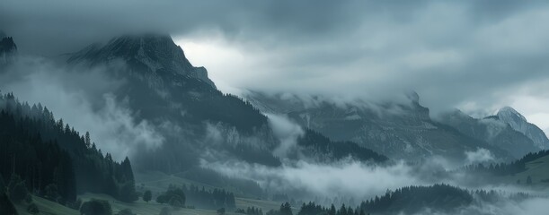 A mountain range shrouded in thick fog and clouds, creating a mystical and obscured landscape in the distance. - obrazy, fototapety, plakaty
