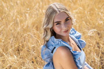 Naklejka na ściany i meble Young beautiful blonde girl posing in a wheat field
