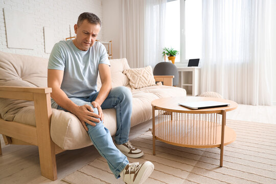 Mature man suffering from knee pain at home