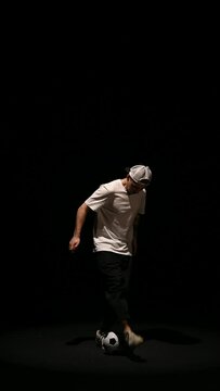 football freestyle performed by a young guy on a black background with a ball. High quality footage