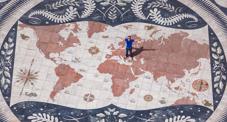 Aerial view of tourist man standing on the giant mosaic of a world map and compass at the discoveries monument, Lisbon, Portugal. Monument of Discoveries Padrao dos Descobrimentos in district Belem