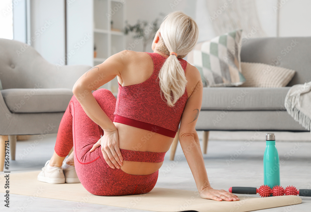 Sticker Sporty mature woman suffering from back pain at home