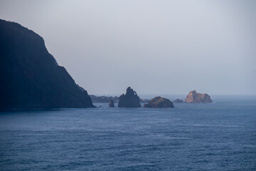 Scenic view of majestic sea stacks Ilheus da Janela Atlantic Ocean seen from idyllic volcanic black sand beach Praia Seixal, Porto Moniz, Madeira island, Portugal, Europe. Surrounded by steep cliffs