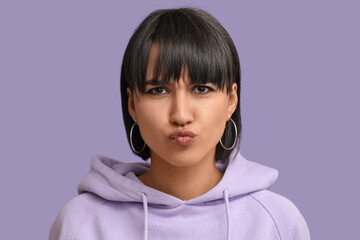 Stylish young woman with nose piercing on lilac background