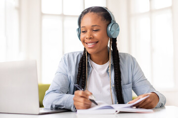 Black lady student studying with headphones on