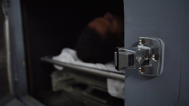 Zoom out from morgue handle to corpse and doctor