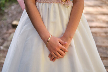 Detalle de las manos y pulsera de una niña vestida de comunión