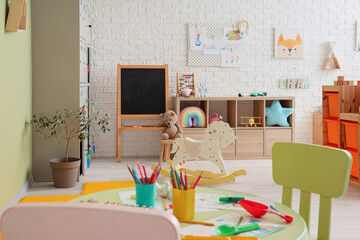 Interior of playroom with table, locker and toys in kindergarten