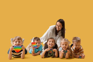 Little children with nursery teacher lying on yellow background