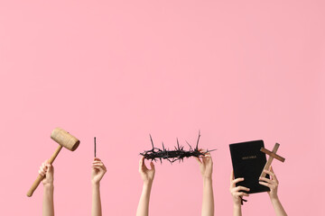 Female hands with crown of thorns, Holy Bible, mallet and cross on pink background