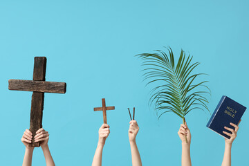 Female hands with wooden crosses, nails, palm leaf and Holy Bible on color background. Good Friday...