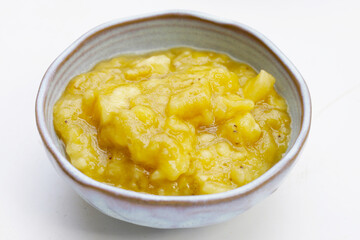 Mashed banana in bowl on white background.