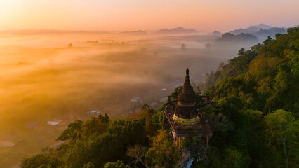 Beautiful sunrise with pagoda on the top of cliff, morning mist at Khao Na Nai Luang Dharma Park, Surat Thani province, Thailand - obrazy, fototapety, plakaty