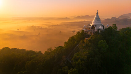 Fototapeta na wymiar Beautiful sunrise with pagoda on the top of cliff, morning mist at Khao Na Nai Luang Dharma Park, Surat Thani province, Thailand
