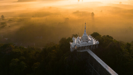 Beautiful sunrise with Buddhist temple on the top of cliff, morning mist at Khao Na Nai Luang Dharma Park, Surat Thani province, Thailand