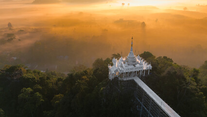 Beautiful sunrise with Buddhist temple on the top of cliff, morning mist at Khao Na Nai Luang...